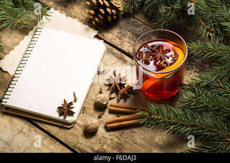 Weihnachten dekorativer Hintergrund mit traditionellen Heißgetränk. Glühwein Wein Rezept Hintergrund mit Notebook und Gewürzen Stockfoto