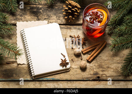Weihnachten dekorativer Hintergrund mit traditionellen Heißgetränk. Glühwein Wein Rezept Hintergrund mit Notebook und Gewürzen Stockfoto