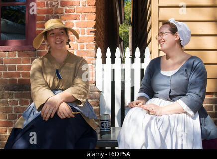 Zwei junge lächelnde Frauen in historischen Kostümen im Colonial Williamsburg, Virginia, USA Stockfoto