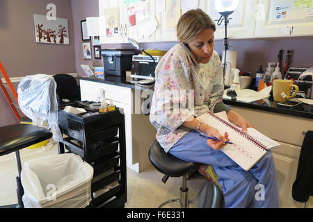 Potomac, USA. 2. November 2015. Lauren Salzberg (R), auch bekannt als Läuse-Lady, spricht über ihr Telefon organisieren Termine mit Kunden in ihrem Studio, einer umgebauten Garage, in Potomac, USA, 2. November 2015. Alle Kunden haben das gleiche Problem, Kopfläuse leiden. So genannte Läuse-Damen wie Salzberg, behandeln ihre Kunden mit Sorgfalt, Geduld, Haarspülung und einem Läusekamm. Foto: Andrea Barthelemy/Dpa/Alamy Live News Stockfoto