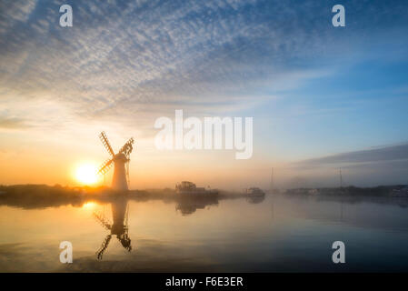 Stunnnig Landschaft mit Windmühle und Fluss bei Sonnenaufgang am Sommermorgen Stockfoto