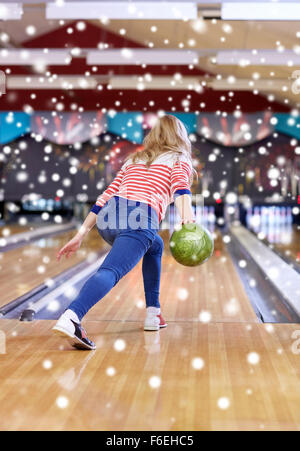 glückliche junge Frau wirft Ball in Bowlingclub Stockfoto