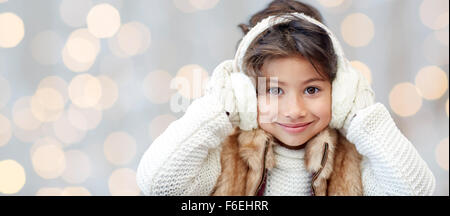 glückliche kleine Mädchen in Ohrenschützer auf Urlaub Lichter Stockfoto