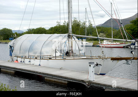 Ein Segelboot mit einer Schutzabdeckung, festgemacht an der Caledonian Canal auf treppenartigen in der Nähe von Fort William Stockfoto