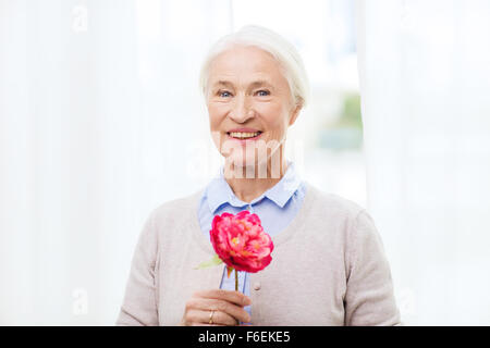 glücklich lächelnd senior Frau mit Blume zu Hause Stockfoto