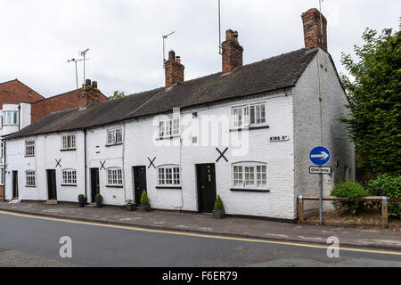 Eine Reihe von fünf weißen terrassenförmig angelegten Hütten mit Wand knüpft in Knutsford, Cheshire, England, UK Stockfoto