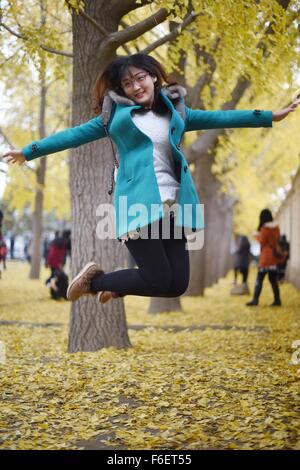 Peking, China. 17. November 2015. Ein Tourist posiert für Fotos unter Ginkgo-Bäume auf einer Straße nahe Diaoyutai State Guesthouse in Peking, China, 17. November 2015. Bildnachweis: Chen Yehua/Xinhua/Alamy Live-Nachrichten Stockfoto