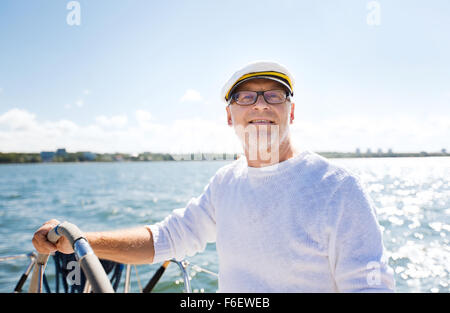 ältere Mann am Ruder auf Boot oder Yacht Segeln im Meer Stockfoto