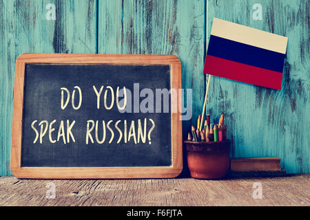 eine Tafel mit der Frage sprichst du Russisch? geschrieben, einen Topf mit Bleistiften, einige Bücher und der Flagge von Russland, auf eine Stockfoto