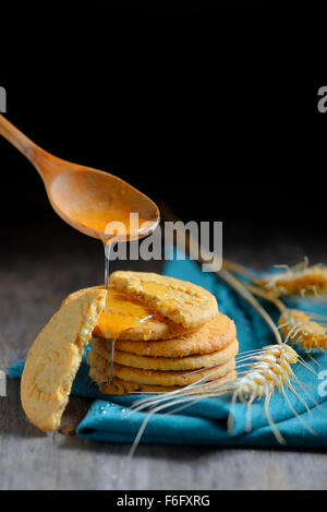 knusprige Müsli-Cookies und Honig auf rustikalen Holztisch Stockfoto