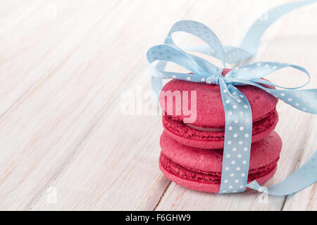 Roten Macarons mit blauem Band auf weißer Holztisch Stockfoto