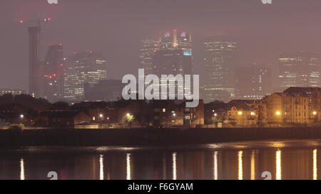 Canary Wharf Financial District Bürogebäude im Nebel mit Residential Gebäuden reflektiert in Themse, London, UK Stockfoto