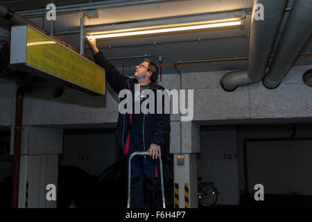 Hausmeister ändert eine Leuchtstofflampe in eine Tiefgarage zur Verfügung. Stockfoto