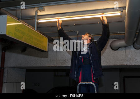 Hausmeister ändert eine Leuchtstofflampe in eine Tiefgarage zur Verfügung. Stockfoto