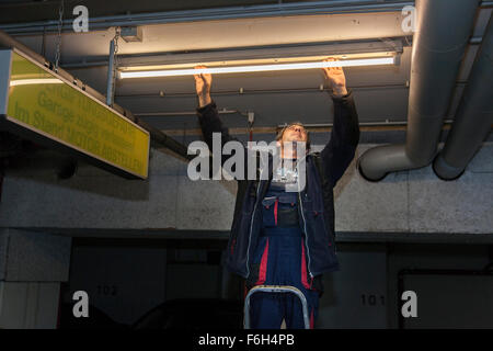 Hausmeister ändert eine Leuchtstofflampe in eine Tiefgarage zur Verfügung. Stockfoto