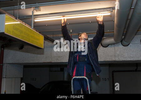 Hausmeister ändert eine Leuchtstofflampe in eine Tiefgarage zur Verfügung. Stockfoto