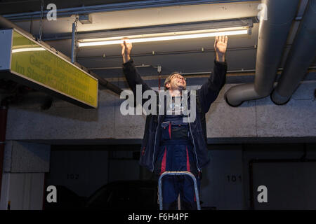 Hausmeister ändert eine Leuchtstofflampe in eine Tiefgarage zur Verfügung. Stockfoto