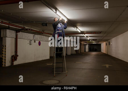 Hausmeister ändert eine Leuchtstofflampe in eine Tiefgarage zur Verfügung. Stockfoto