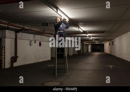 Hausmeister ändert eine Leuchtstofflampe in eine Tiefgarage zur Verfügung. Stockfoto