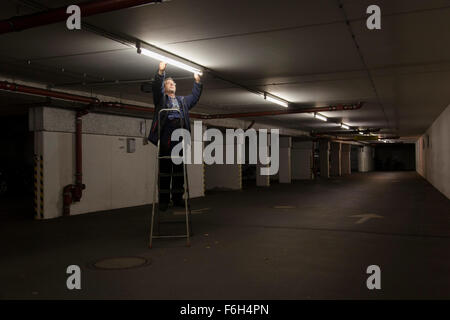 Hausmeister ändert eine Leuchtstofflampe in eine Tiefgarage zur Verfügung. Stockfoto