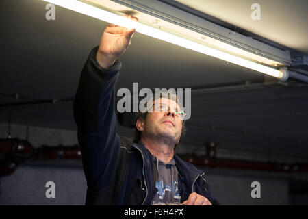 Hausmeister ändert eine Leuchtstofflampe in eine Tiefgarage zur Verfügung. Stockfoto