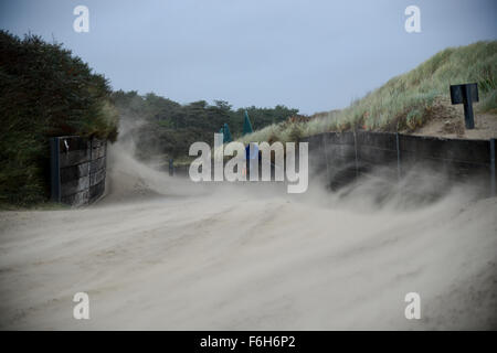 Pembrey Strand, Süd-Wales, UK, Dienstag, 17. November 2015. Trotz Gales Böen bis zu 50 km/h in den südlichsten Teilen von Wales kämpft ein Mann um ein Fahrrad auf dem Weg zum Strand gegen wirbelnden und Flugsand, Pembrey Country Park, in der Nähe von Llanelli, Carmarthenshire, Wales, UK zu schieben. Stockfoto