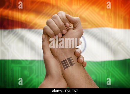 Barcode-ID Nummer Tätowierung am Handgelenk der dunkle enthäutete Person und Nationalflagge auf Hintergrund - Indien Stockfoto