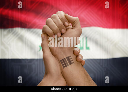 Barcode-ID Nummer Tätowierung am Handgelenk der dunkle enthäutete Person und Nationalflagge auf Hintergrund - Irak Stockfoto