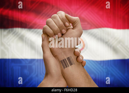 Barcode-ID Nummer Tätowierung am Handgelenk der dunkle enthäutete Person und Nationalflagge auf Hintergrund - Paraguay Stockfoto