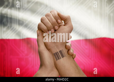 Barcode-ID Nummer Tätowierung am Handgelenk der dunkle enthäutete Person und Nationalflagge auf Hintergrund - Polen Stockfoto