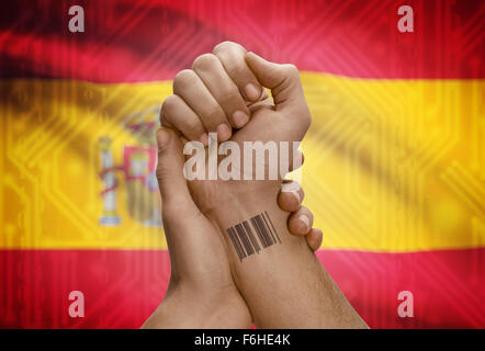 Barcode-ID Nummer Tätowierung am Handgelenk der dunkle enthäutete Person und Nationalflagge auf Hintergrund - Spanien Stockfoto