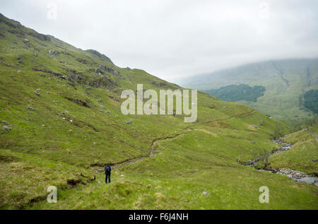 Eine einsame Frau zu Fuß in die obere Mittellauf des Glen Finnan an einem nasskalten Novembertag in den Hügeln Stockfoto