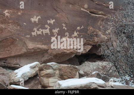 Eine Darstellung der vier Reiter auf dem Rücken der Pferde, Hunde und eine Herde Dickhornschafe Petroglyphen. Stockfoto