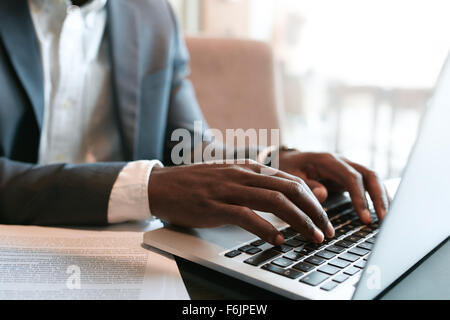 Geschäftsmann, arbeiten am Laptop mit einige Dokumente auf Tabelle. Hautnah auf männliche Hände auf Laptoptastatur tippen. Stockfoto