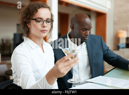 Schuss der Geschäftsfrau mit einem Glas cocktail mit ein Business-Mann sitzen am Tresen. Geschäftsleute, die im Café sitzen ein Stockfoto