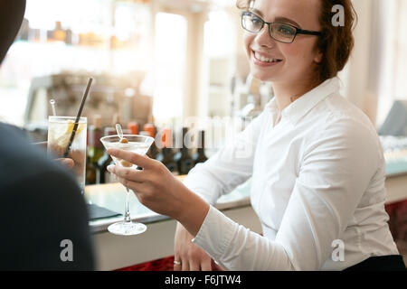 Junge Geschäftsfrau Toasten Getränke mit Kollegen im Café. Kaukasische Geschäftsfrau mit Partner ein Glas Getränk in Bar Stockfoto