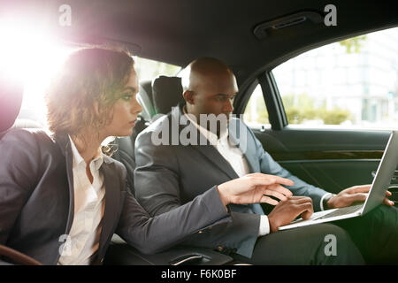 Schuss von Jungunternehmen ordnet Reisen in Luxus-Auto auf dem Rücksitz arbeiten am Laptop arbeiten. Besprechen Sie Geschäft stra Stockfoto