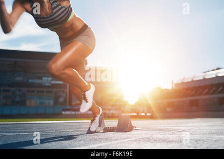 Zugeschnittenen Schuss junge Sportlerin aus der Startlinie in einem Rennen starten. Weibliche Läufer begann der Sprint vom Ausgangspunkt Stockfoto