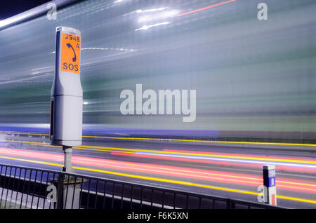 Notfall-Telefon in der Nacht von M48 Autobahn in der Nähe der Severn-Brücke. LKW Lichtspuren werden angezeigt. Stockfoto