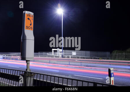 Notfall-Telefon in der Nacht von M48 Autobahn in der Nähe der Severn-Brücke. Auto Licht Wege werden angezeigt. Stockfoto