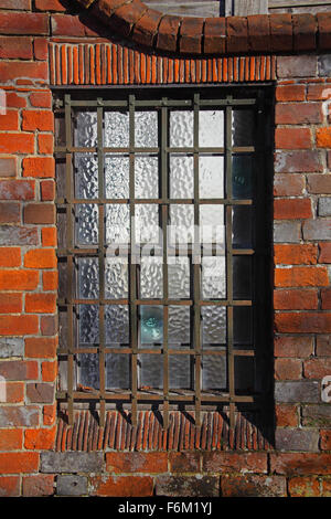 Ein sehr altes vergitterten Bleiglas Fenster mit mundgeblasenes Glas und alten Mauerwerk umgeben. Stockfoto