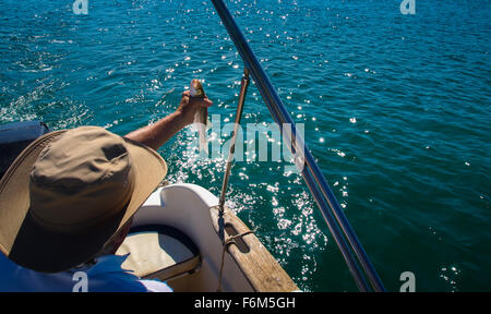 Fischer im Boot mit Seebarsch in seiner hand Stockfoto