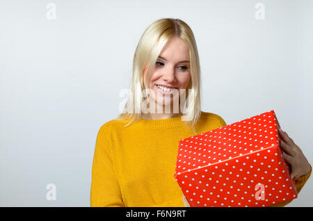 Glücklich blonde junge Frau mit roten Geschenkbox vor weißem Hintergrund. Stockfoto