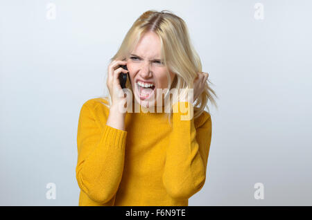 Eine halbe Stelle erschossen einer wütenden jungen Frau Gespräch mit jemandem über das Handy, zeigt ein offenes Lächeln. Stockfoto