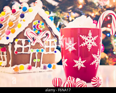 Lebkuchenhaus mit Bonbons mit Weihnachtsbaum in der Backgound verziert. Stockfoto