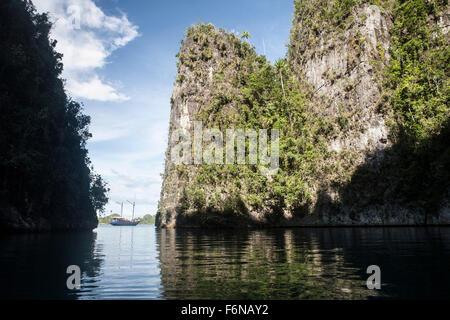 Zerklüfteten Kalksteininseln umrahmen eine indonesische Pinisi-Schoner in einem abgelegenen Teil von Raja Ampat, Indonesien. Diese schöne Region ist Stockfoto