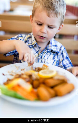 Nettes Kind alleine essen mit den Händen Stockfoto