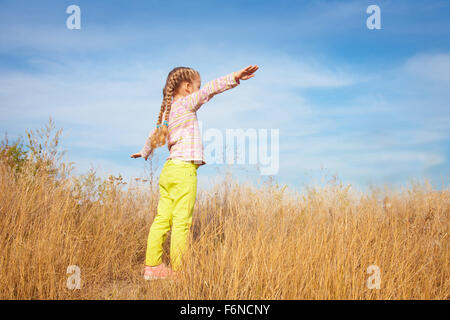 Kleines Mädchen in helle Kleidung stehen gegen den Himmel in einem Feld Stockfoto