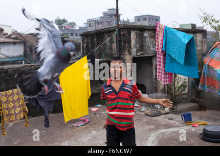 DHAKA, Bangladesch-17. November: ein Kind spielt mit einer Taube auf dem Dach eines alten Buildingin alten Dhaka am 17. November 2015. Alten Dhaka ist ein Begriff verwendet, um die historische Altstadt von der modernen Hauptstadt Dhaka beziehen. Es wurde im Jahre 1608 als Jahangir Nagar, der Hauptstadt von Mughal Bengal gegründet. Stockfoto