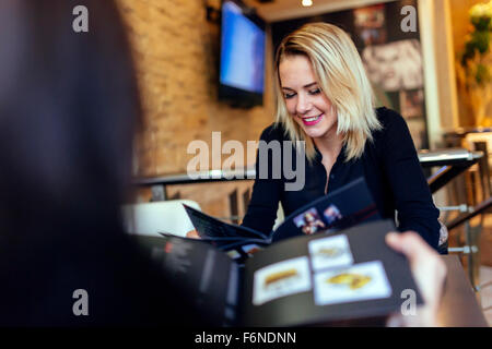 Zwei Frauen, die vor der Bestellung im Café mit Blick auf Menü Stockfoto